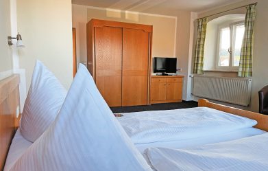 Zimmer mit Doppelbett und Schrank im Hintergrund.